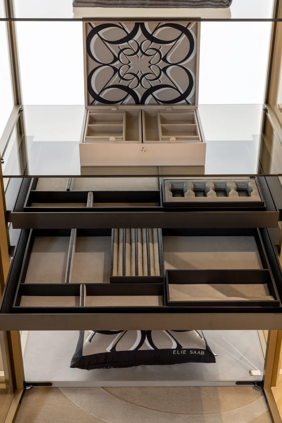 Open wardrobe drawer with jewelry trays behind glass