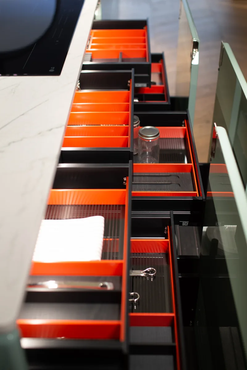 Schiffini drawers with red-lined organizers beneath a sage-green kitchen