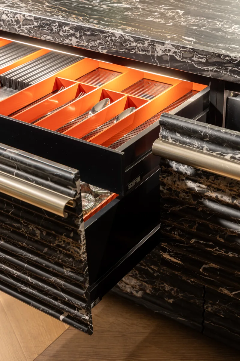 Schiffini drawers in a black marble island with red-lined cutlery trays
